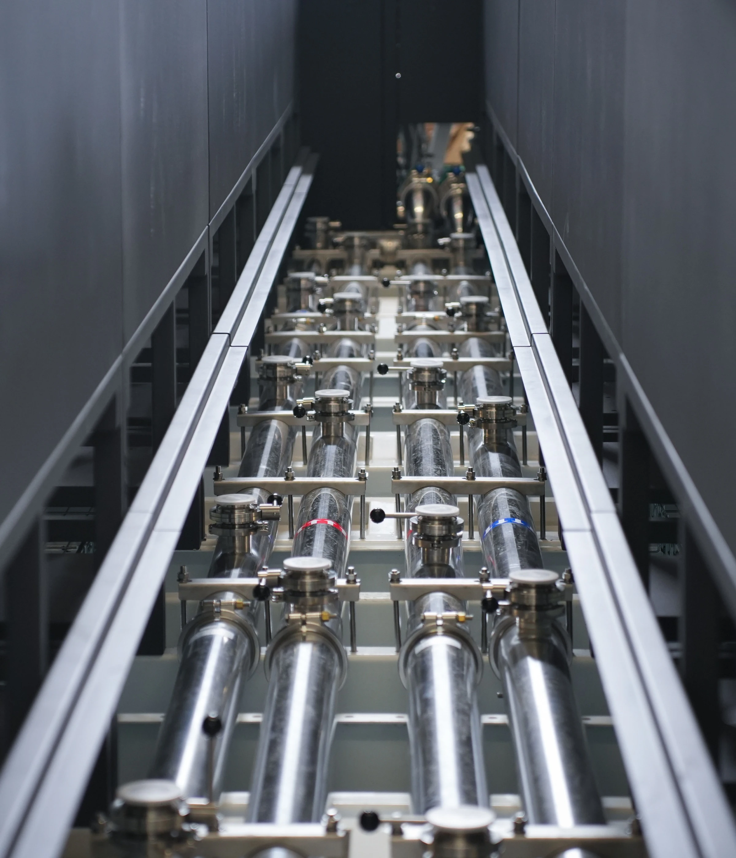 Looking down the CDU skid inside a container: rows of clear filtration housings on stainless clamps, valve handles paired red and blue for flow and return