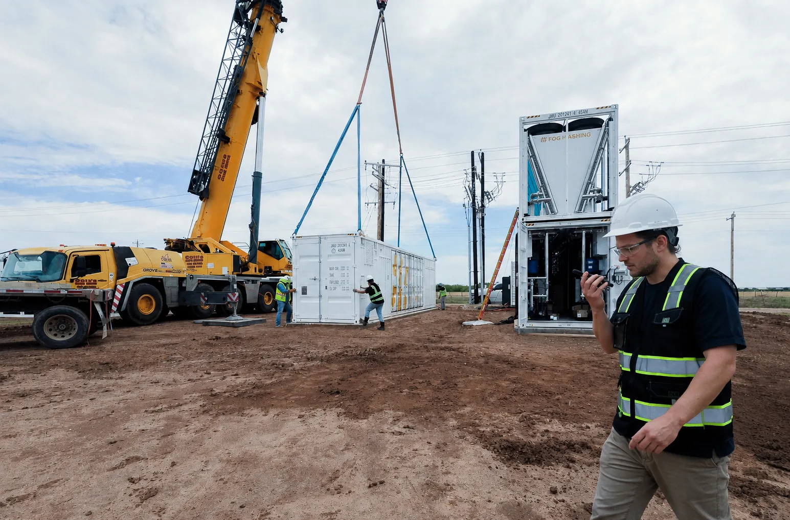 Fog crew on site: a container being craned onto its pad while an engineer directs the lift by radio