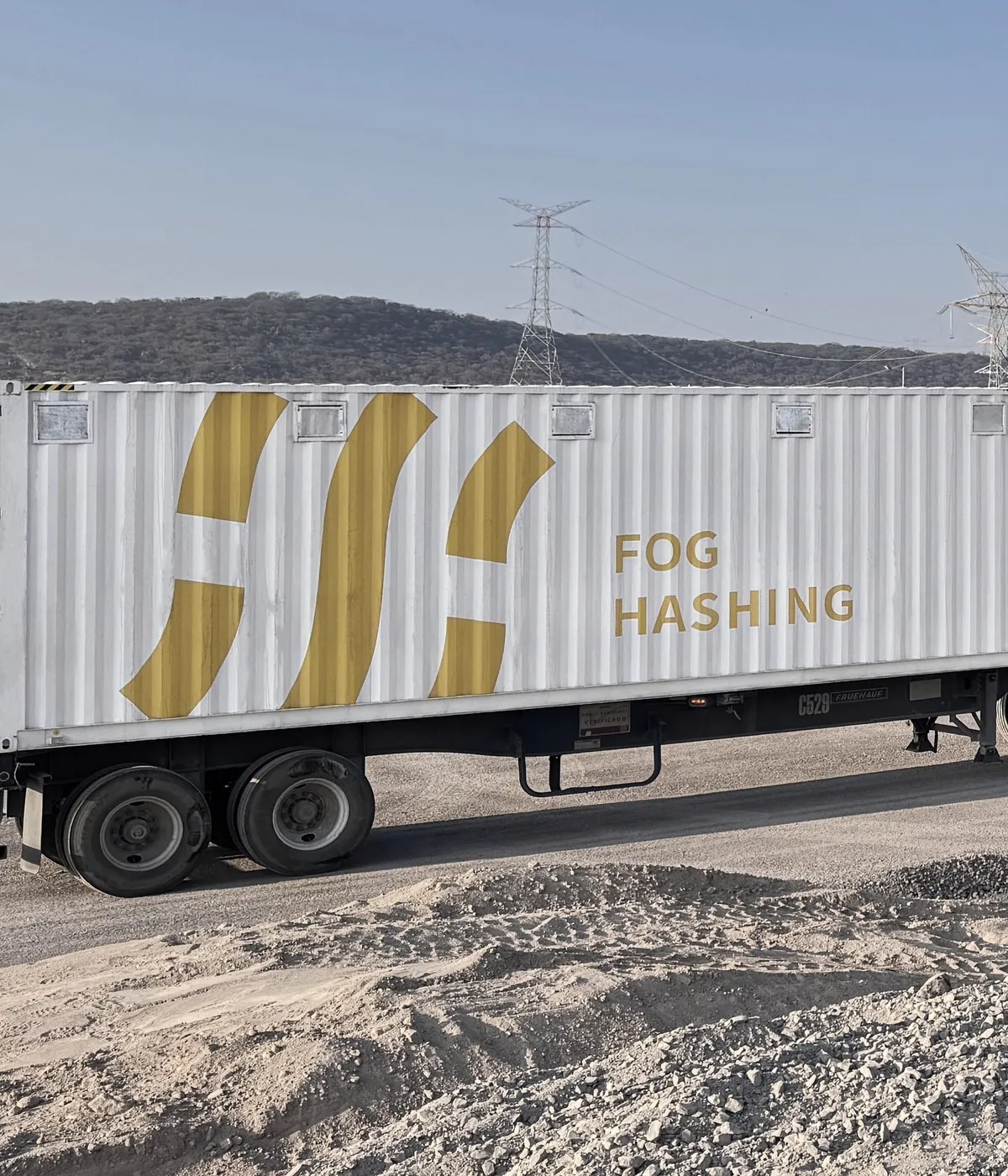 A Fog Hashing container on its trailer at a substation site, hills and transmission towers behind it