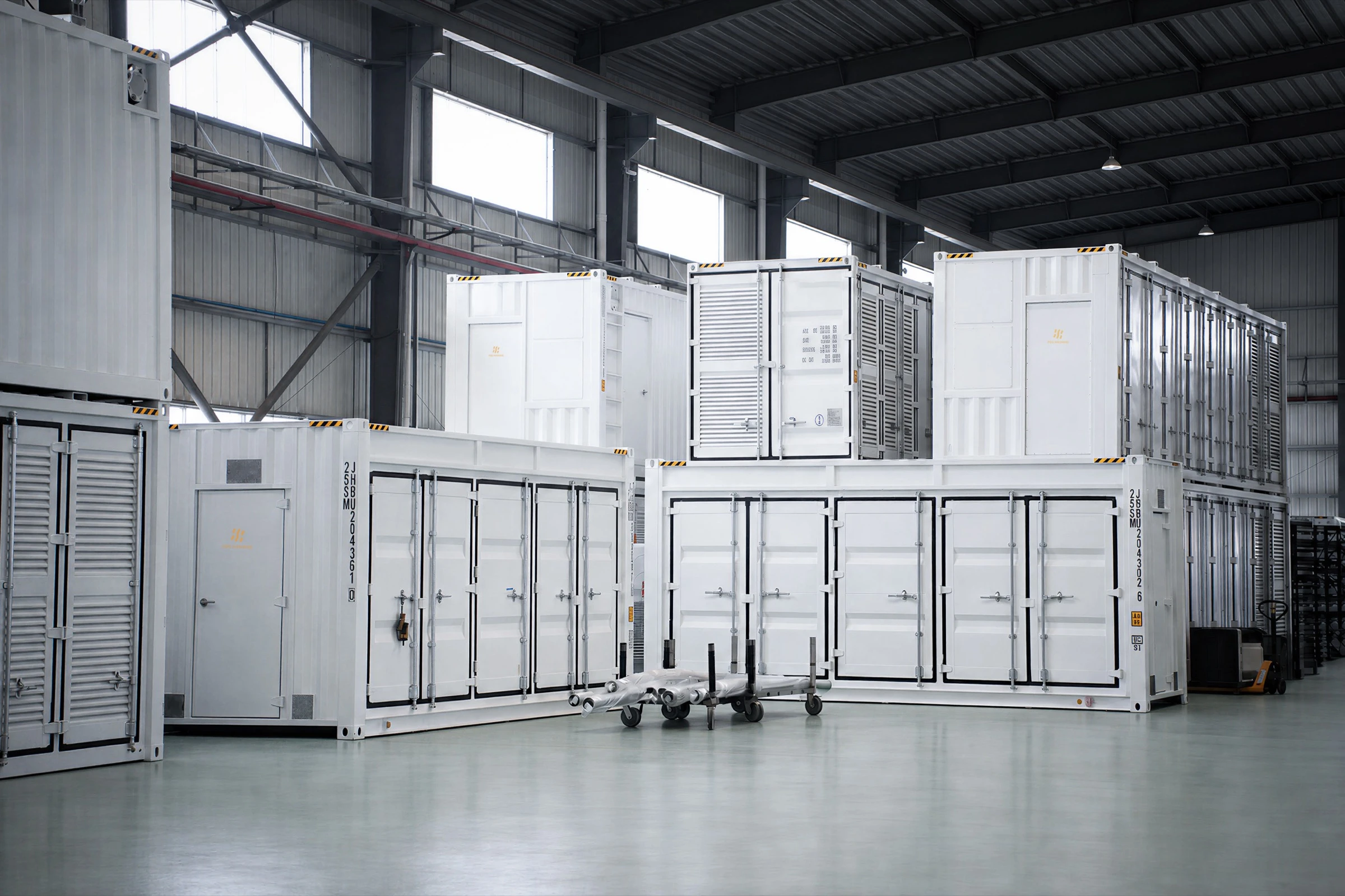 Finished container modules staged on the factory floor, stacked two high down the bay