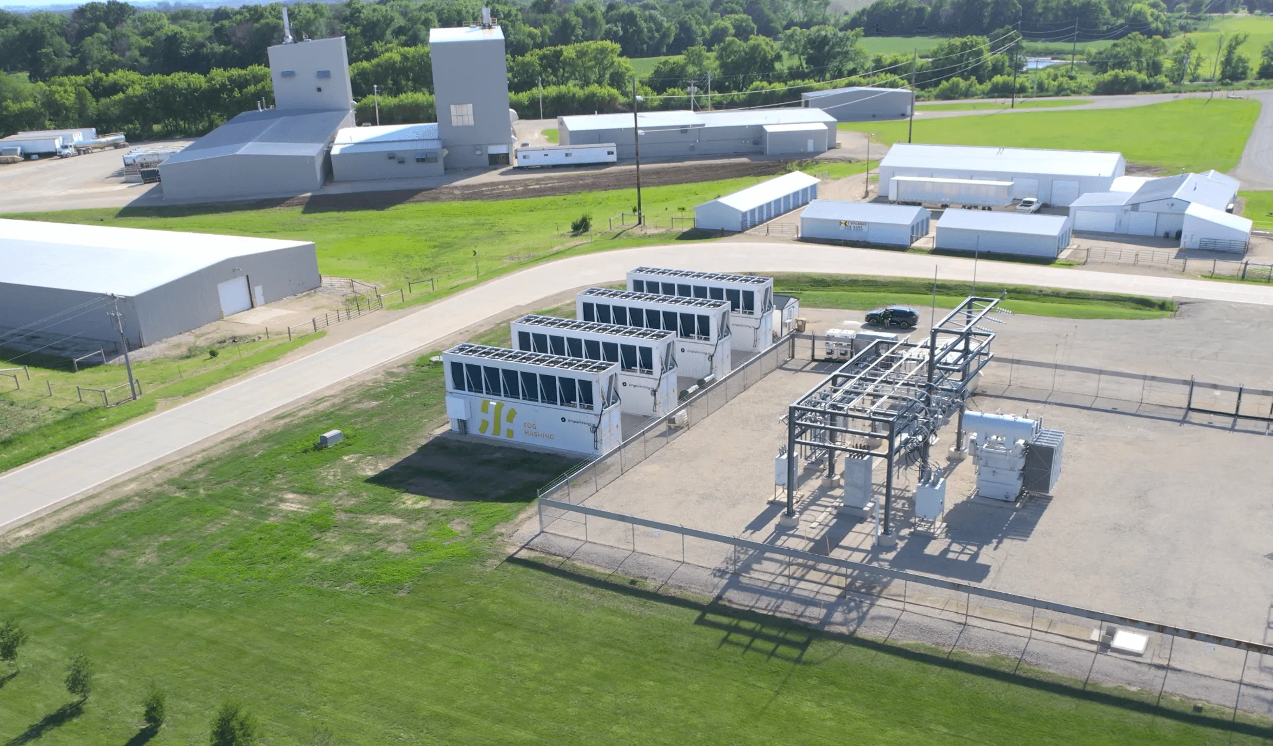 Aerial of a Fog Hashing site: four immersion containers under dry coolers, beside the substation feeding them
