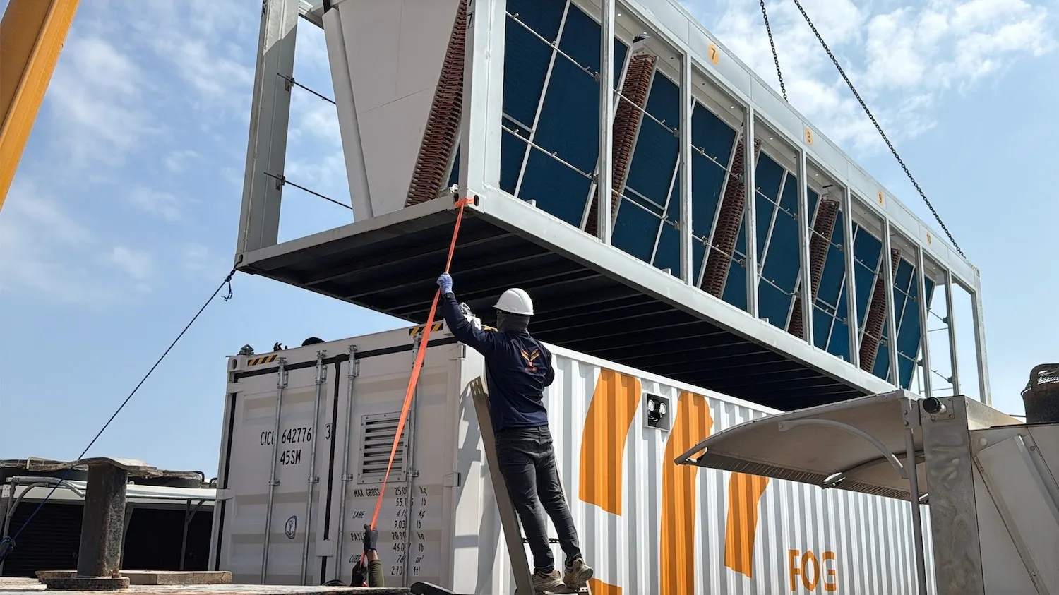 A container roof section being craned into place