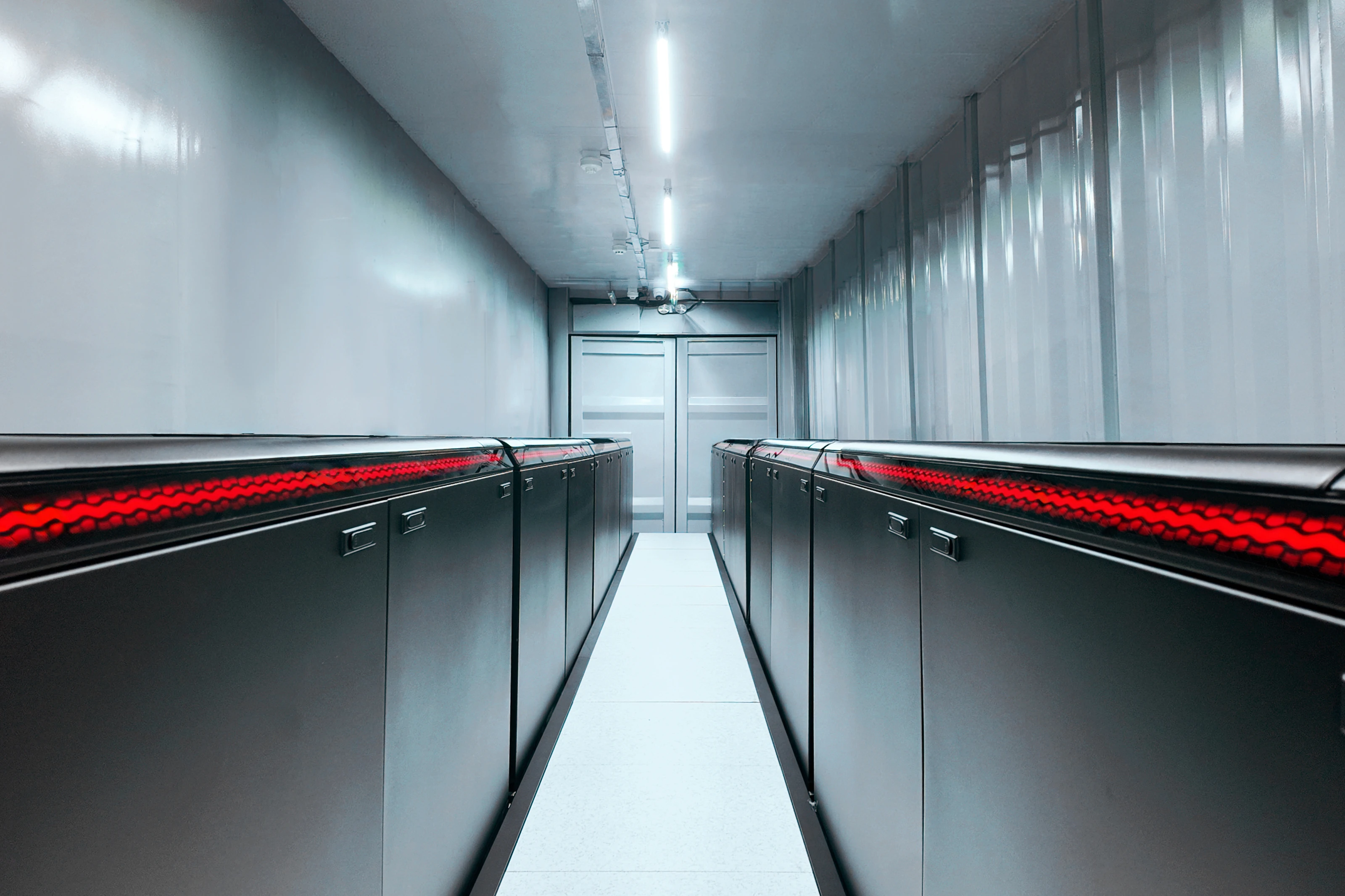 The aisle of a FogPod Imm container, tank rows on either side with their red lightbars lit