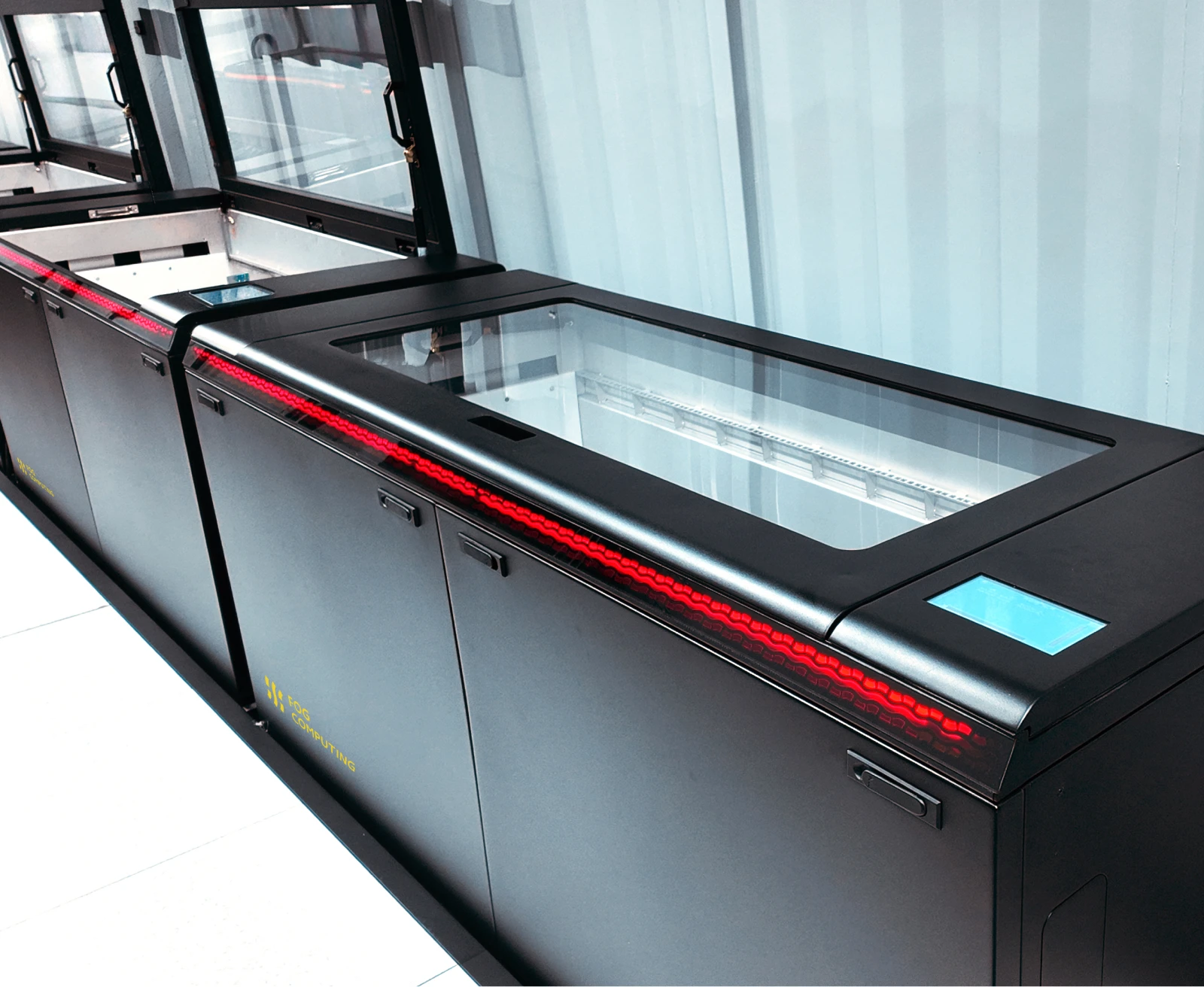 A FogPod Imm tank with its glass lid closed, the red status lightbar running its length and the Fog Computing mark on the cabinet