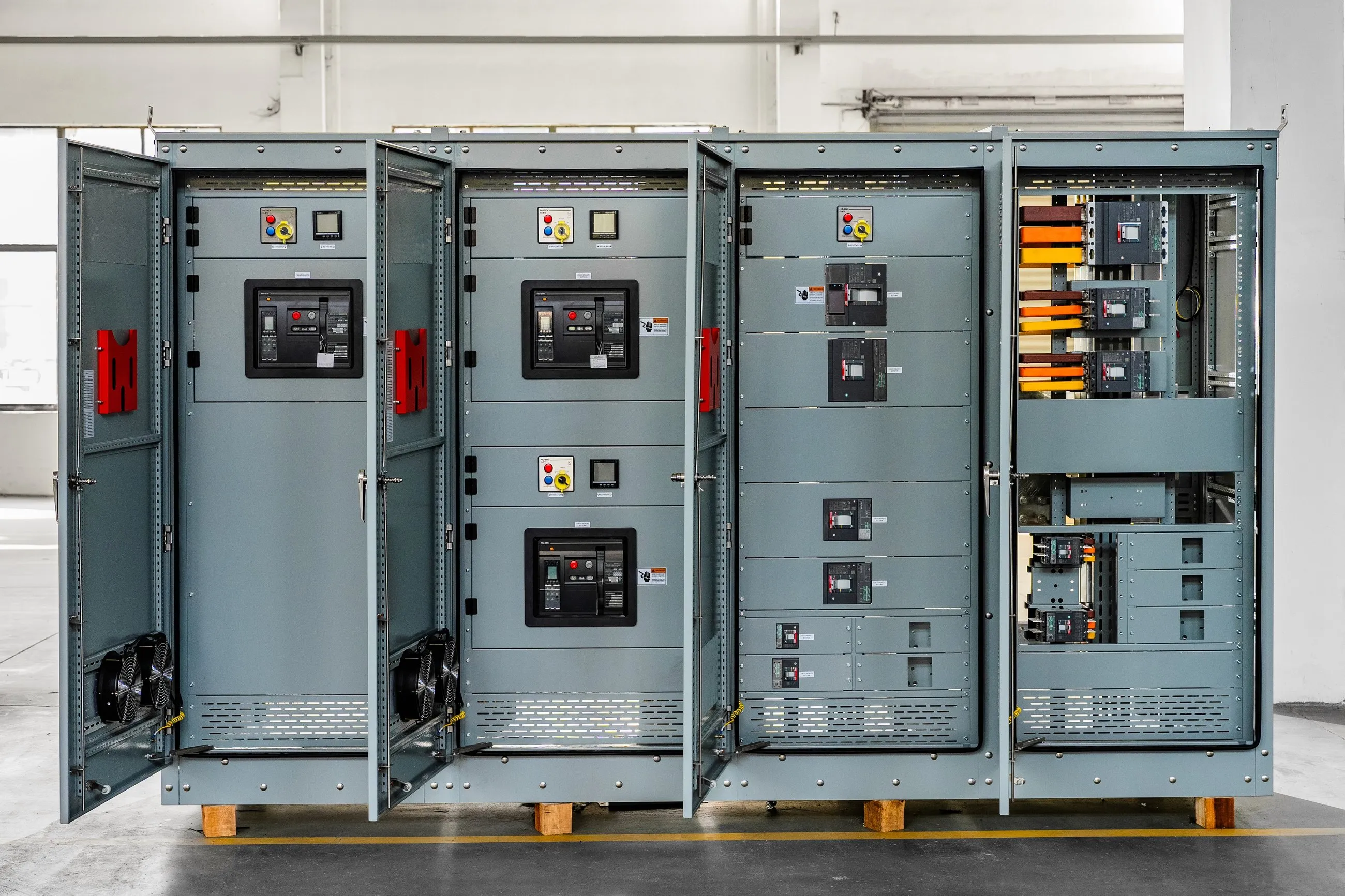 Switchboard cubicles open on the floor, breakers and listings visible